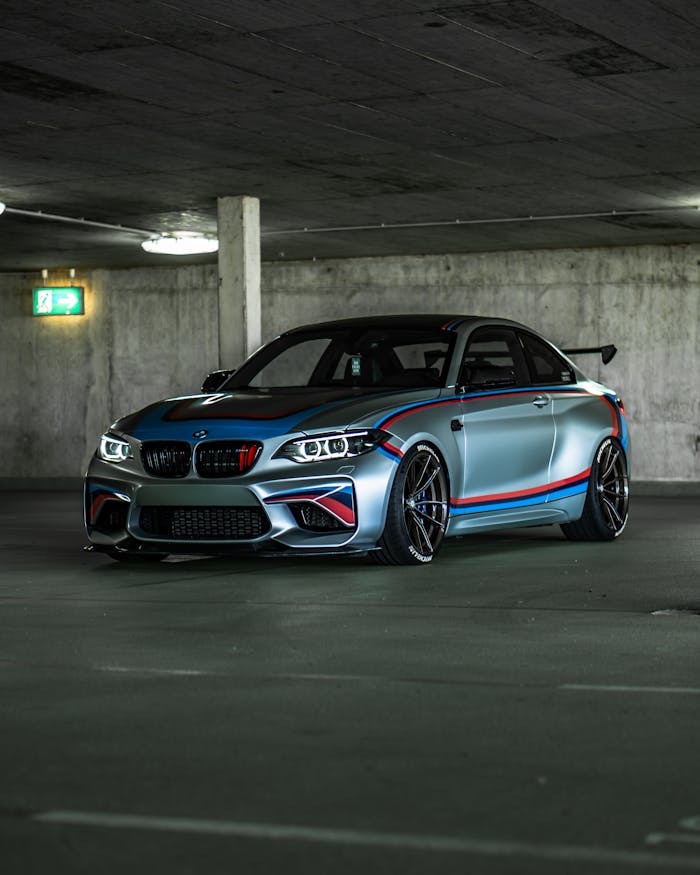A custom BMW M2 car parked stylishly in an underground garage setting.